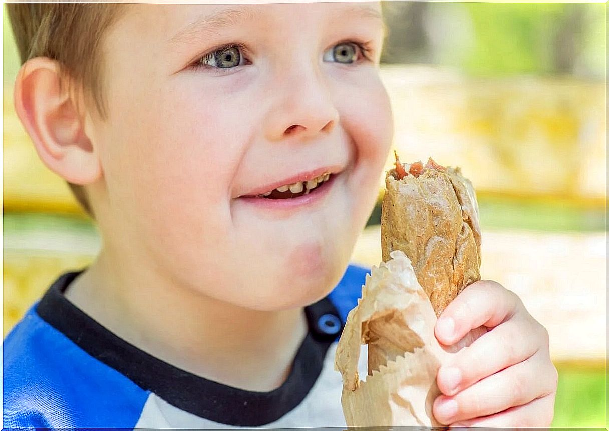 Child eating a sandwich with whole grain bread.