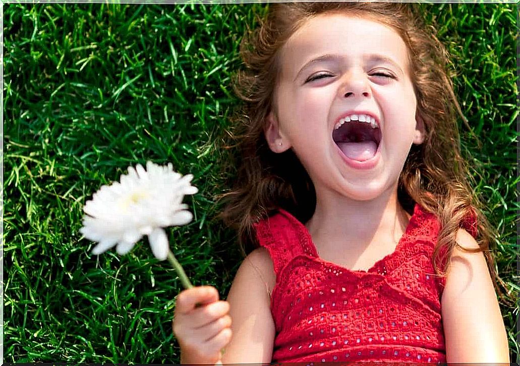 Girl holding flower smiling.